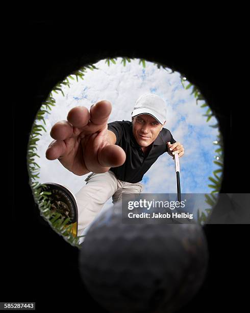 view through hole of golfer reaching for golf ball - golf ball hole stock pictures, royalty-free photos & images