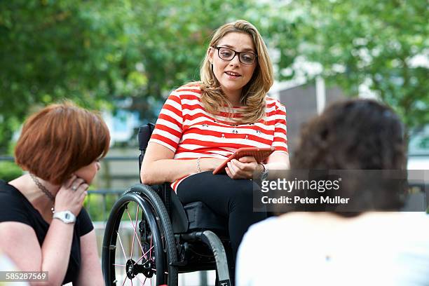 female student in wheelchair chatting to friends on college campus - 3 teenagers mobile outdoors stock-fotos und bilder