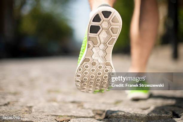 runner jogging on cobbled street - schoenzool stockfoto's en -beelden