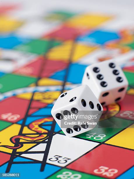 dice falling onto snakes and ladders board - board game photos et images de collection