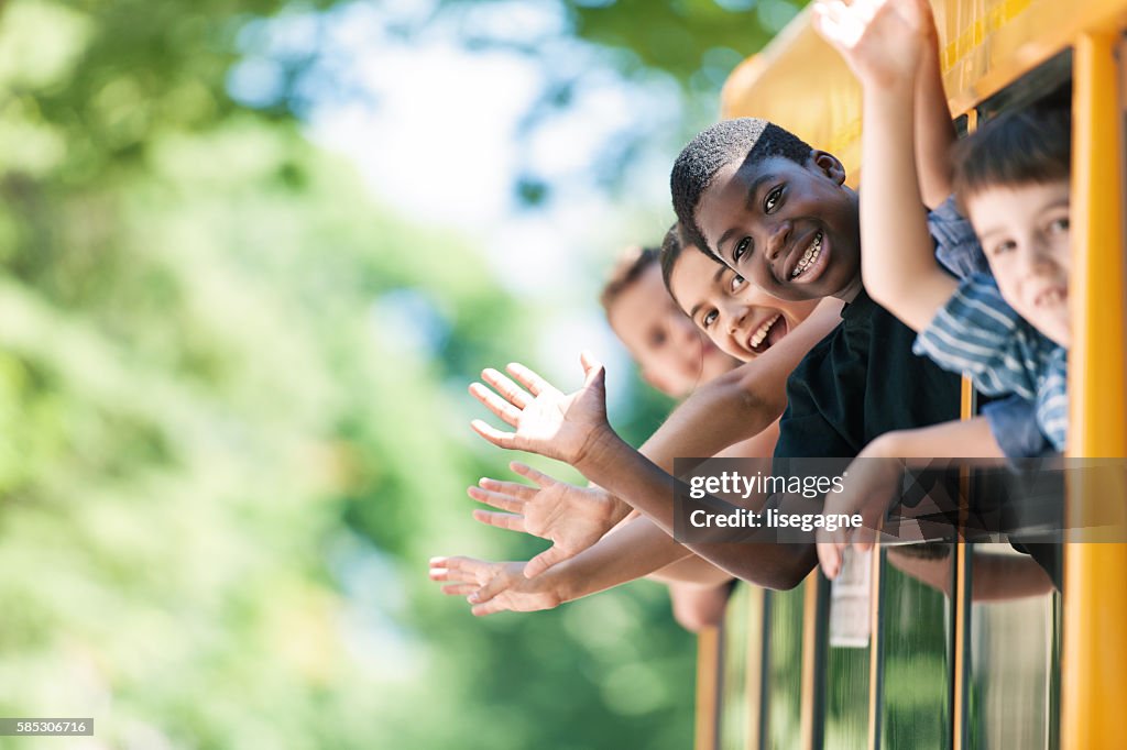 School kids hanging out bus windows