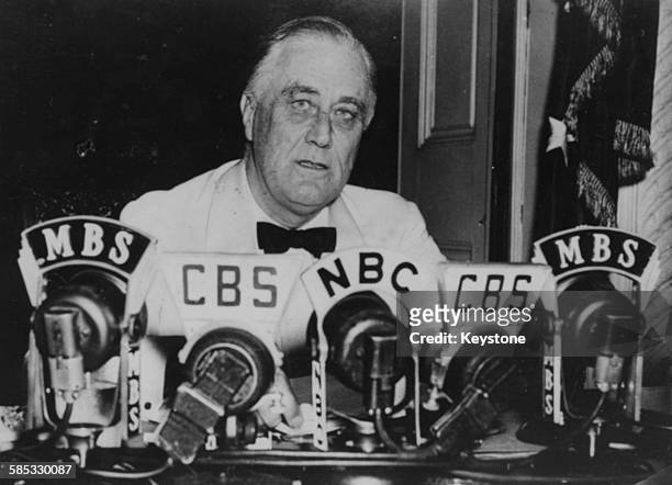 President Franklin D Roosevelt making a speech in front of a bank of microphones, in which he is declaring an unlimited state of emergency during...