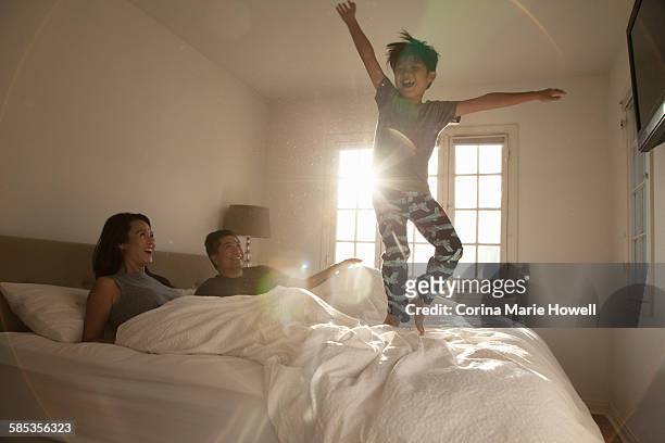 boy jumping on parents bed - children jumping bed stock pictures, royalty-free photos & images