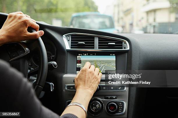 woman sitting in car, using gps, focus on hands - gps ストックフォトと画像