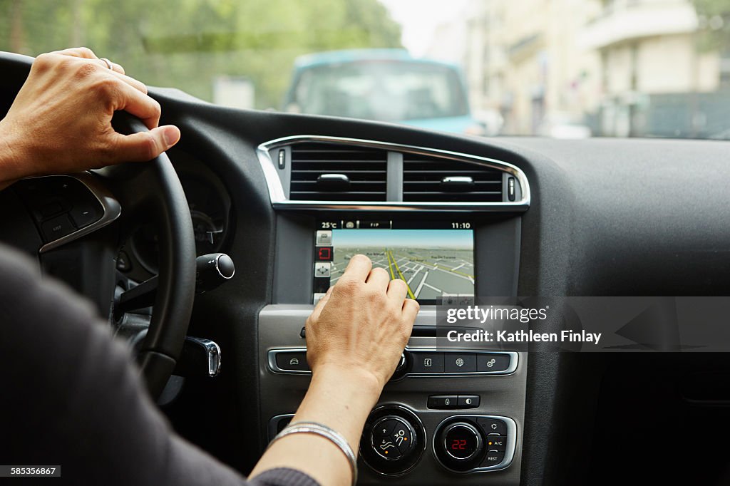Woman sitting in car, using gps, focus on hands