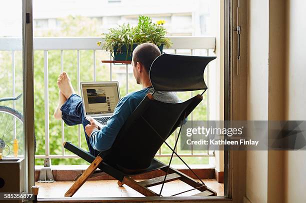 man using laptop on balcony - balcony stock photos et images de collection