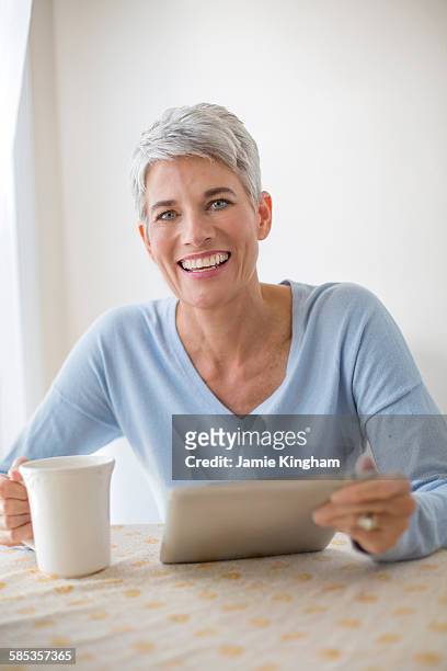 portrait of grey haired mature woman with blue eyes using digital tablet - nevada homes stock pictures, royalty-free photos & images