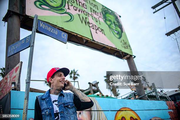 graffiti artist using smartphone under street signs, venice beach, california, usa - graffiti hintergrund stock pictures, royalty-free photos & images