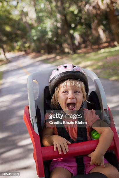 young girl sitting in childs bicycle seat, enjoying journey - fahrradsattel stock-fotos und bilder