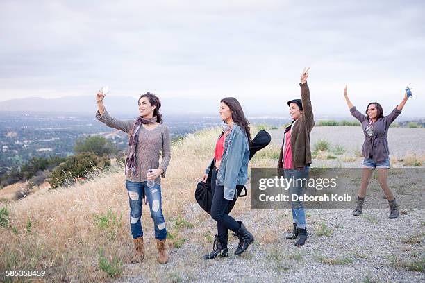 four adult sisters posing for smartphone selfie on rural hill - la four stock pictures, royalty-free photos & images