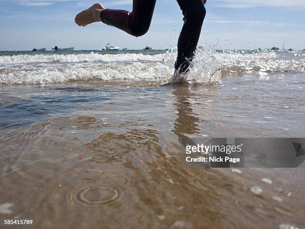person wearing wetsuit splashing through sea - feet run in ocean stock pictures, royalty-free photos & images
