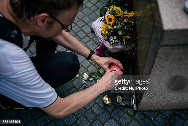 People mourn near the crime scene and lay flowers outside the OEZ shopping center the day after a shooting spree left nine victims dead on July 23,...