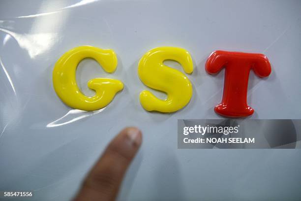 An Indian consumer goods trader shows letters GST representing "Goods and Services Tax" at his shop in Hyderabad on August 3, 2016. Finance Minister...