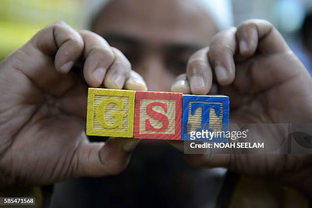 An Indian consumer goods trader shows letters GST representing "Goods and Services Tax" at his shop in Hyderabad on August 3, 2016. Finance Minister...