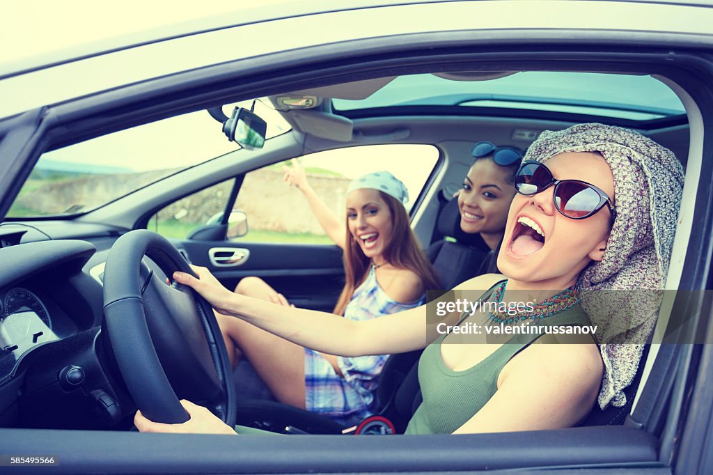 Young boho women traveling and listening music in the car