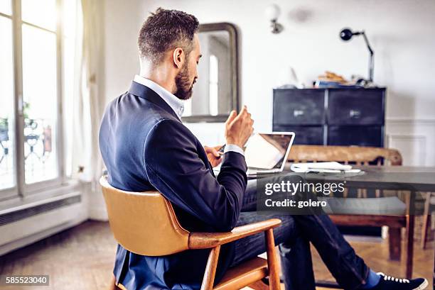 bearded business man looking at mobile in home office - paris stock exchange stockfoto's en -beelden