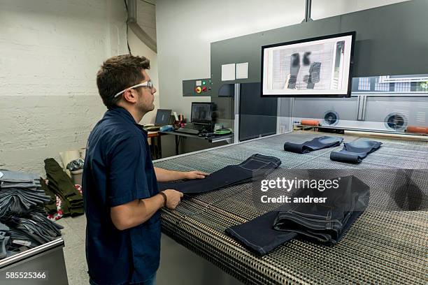 homme maniant une machine laser dans une usine de vêtements - jeans outfit photos et images de collection