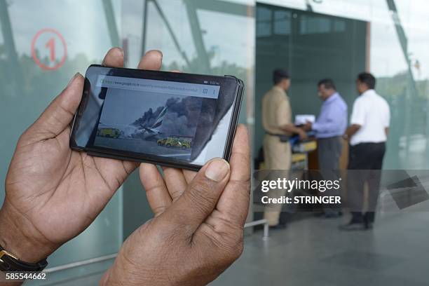 Relative displays a picture of the crashed Emirates aircraft EK521 which flew from Thiruvananthapuram to Dubai, on his mobile phone at the terminal...