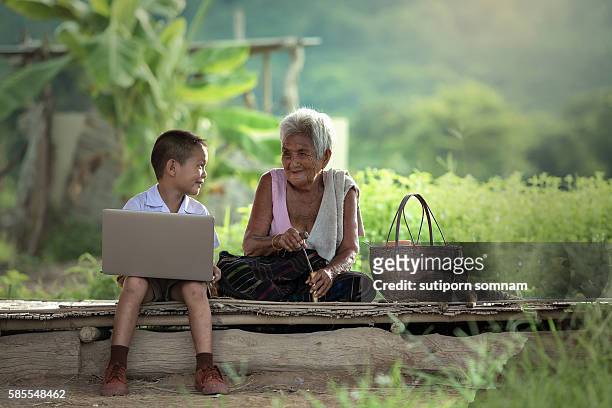 a boy and grandmother with a laptop - boy thailand stock-fotos und bilder