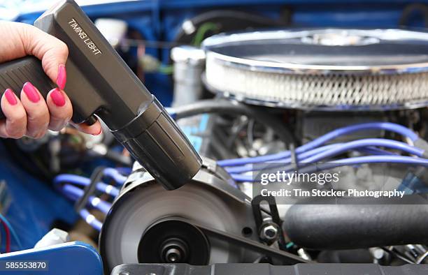 a woman tuning a car engine with a timing light. - car tuning stock pictures, royalty-free photos & images