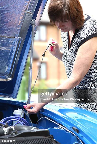 a woman using a dipstick to check the car engine oil level - dipstick stock pictures, royalty-free photos & images