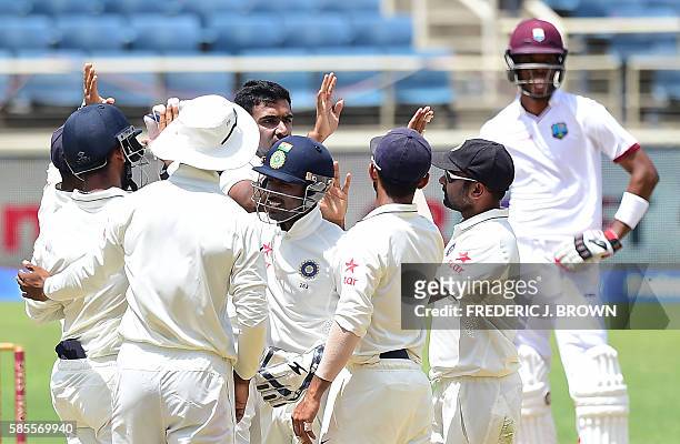 Bowler Ravichandran Ashwin of India celebrates with teammates after his delivery to West Indies batsman Jermaine Blackwood was caught out by...