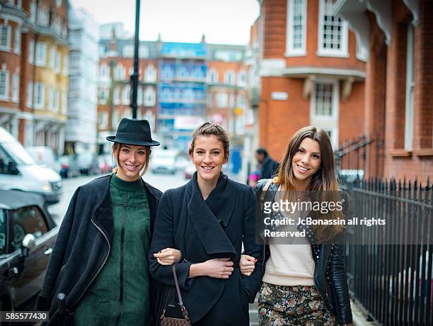 three women smiling and walking on the street - jc bonassin stockfoto's en -beelden