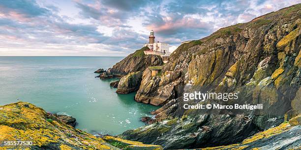 baily lighthouse, howth, county dublin, ireland, europe. panoramic view of the cliff and the lighthouse at sunrise. - irishman stock-fotos und bilder