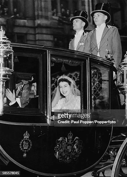 Princess Elizabeth and Prince Philip, the Duke of Edinburgh, wave from the Royal carriage as they return to Buckingham Palace after their wedding at...
