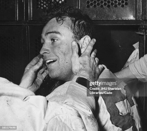 Candid portrait of Johns Hopkins University freshman lacrosse midfielder William Powell sitting in the locker room after a game, 1956. .