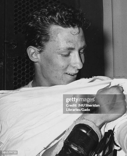 Johns Hopkins lacrosse midfielder Al Seivold smiles while changing, 1956. .