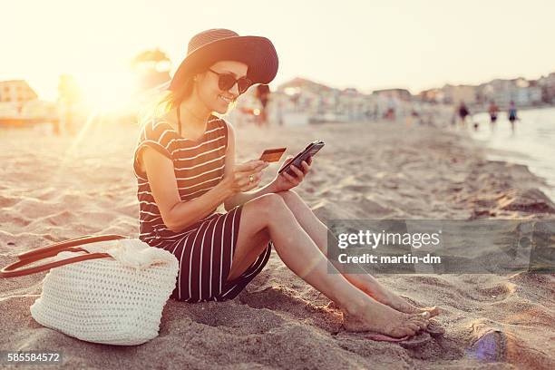 woman using credit card at the beach - spending money stock pictures, royalty-free photos & images