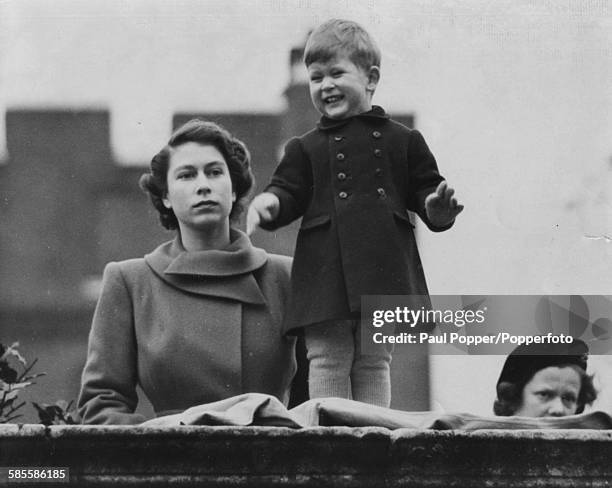 Princess Elizabeth watches Prince Charles smile at the crowds as they wait to view the marriage procession of Queen Juliana and Prince Bernhard to...