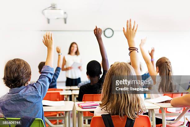 school kids in classroom - armen omhoog stockfoto's en -beelden