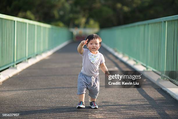 toddler boy pointing finger while walking - chinese baby shoe stock pictures, royalty-free photos & images