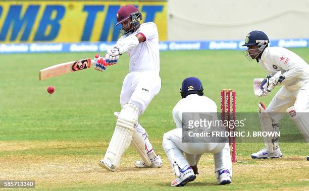Shane Dowrich of the West Indies connects for a hit off a delivery from Ravichandran Ashwin of India as Cheteshwar Pujara and wicket keeper...