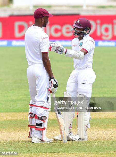 West en Roston Chase and Shane Dowrich touch gloves between the acion against India on day five of their Second Test cricket match on August 3, 2016...