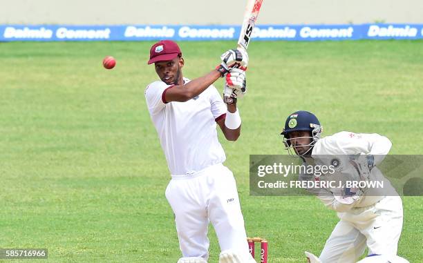 Roston Chase of West Indies connects for a four off a delivery from bowler Ravichandra Ashwin of India as wicket keeper Wriddhiman Saha plays close...
