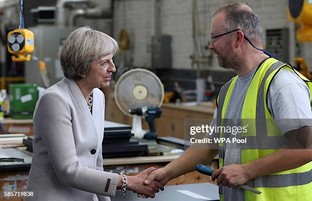 British Prime Minister Theresa May speaks with a worker as she visits Martinek joinery factory on August 3, 2016 in London, United Kingdom.