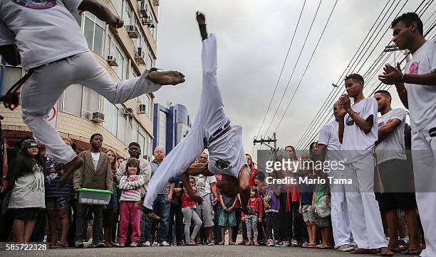 Brazilians perform capoeira, a Brazilian martial art mixing dance and music, ahead of the arrival of the Olympic torch relay in Rio's North Zone on...