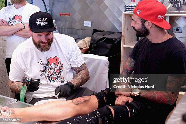 Luke Wessman tattoos a guest at the Kiehl's national LifeRide for amfAR celebration at the NYC flagship store on August 3, 2016 in New York City.