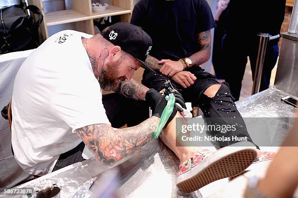 Luke Wessman tattoos a guest at the Kiehl's national LifeRide for amfAR celebration at the NYC flagship store on August 3, 2016 in New York City.