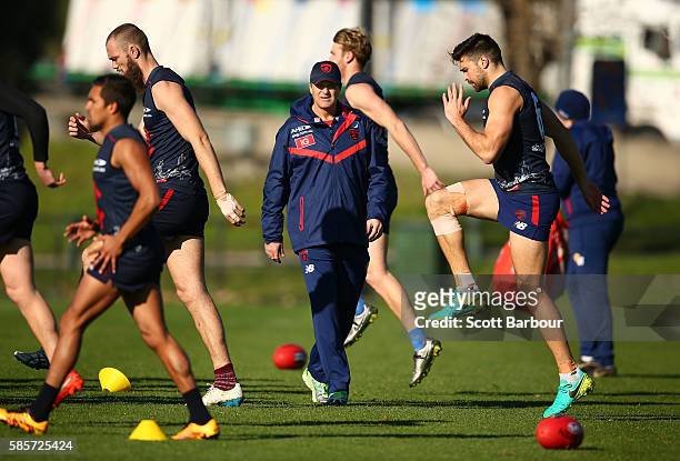Paul Roos, coach of the Demons looks on as Chris Dawes of the Demons warms up during a Melbourne Demons AFL training session at Gosch's Paddock on...