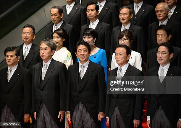 Shinzo Abe, Japan's prime minister, front row center, poses for a group photograph with members of his new cabinet including Taro Aso, Japan's...