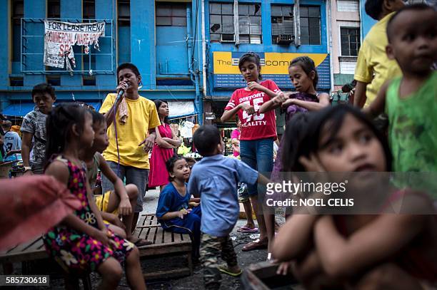 This picture taken on June 8, 2016 shows children waiting their turn to sing karaoke along a street in the Divisoria market in Manila. Since winning...