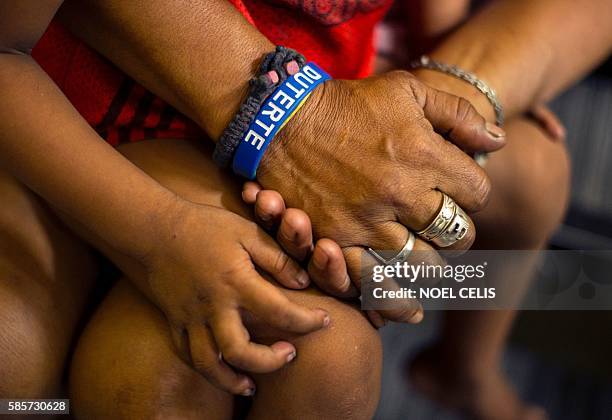 This photo taken on June 8, 2016 shows a mother wearing a "Duterte" wristband as she holds her daughter's hand after she was temporarily detained for...