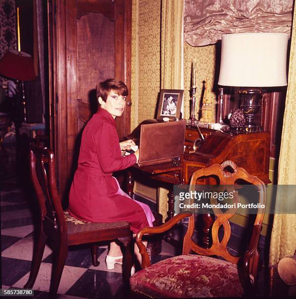Italian actress Franca Valeri in her house sitting at the writing desk. Italy, 1972