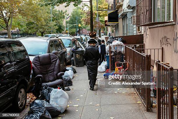 rear view of hasidic jewish family (father and two sons) in traditional clothing walking on the street in williamsburg, new york, usa - hasidic jew stock-fotos und bilder