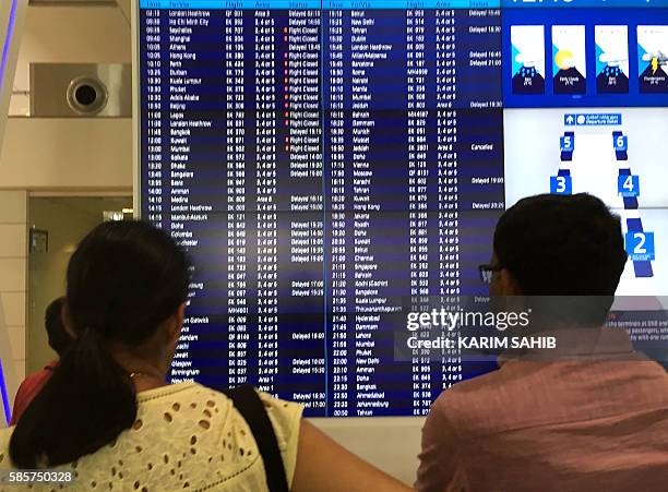 Passengers look at the departures announcement board at Dubai airport a day after an Emirates plane caught fire during a crash-landing, on August 4,...