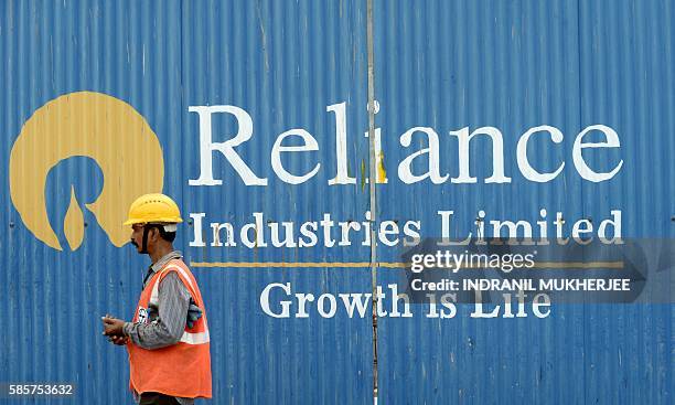 Worker walks past the signage of Reliance Industries Limited at the site of an upcoming highrise at the Bandra Kurla Complex business district in...